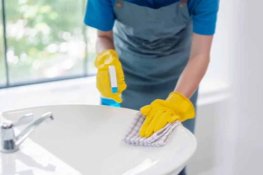 Cleaning service underway as a cleaner wipes basin